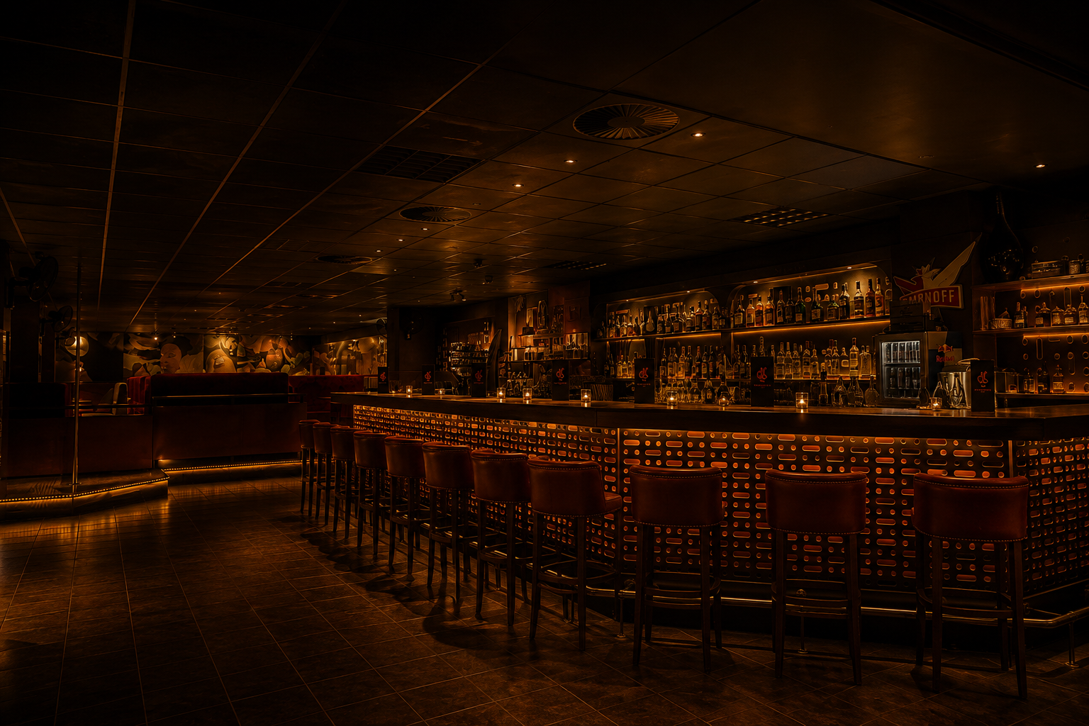 Die lange Bar mit Barhockern und beleuchteten Flaschenregalen
